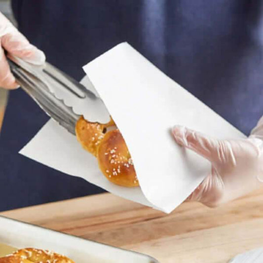 Persoană folosind clești pentru a ridica chifle din coltar hartie alb 11x25cm pt hot dog.